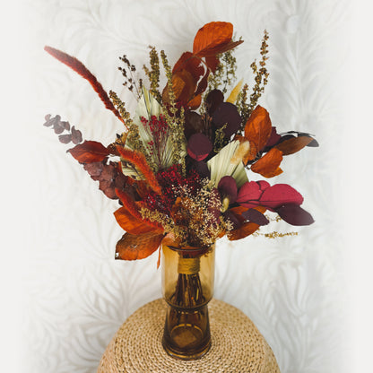 Bouquet of orange, red, and brown dried flowers in a brown glass vase