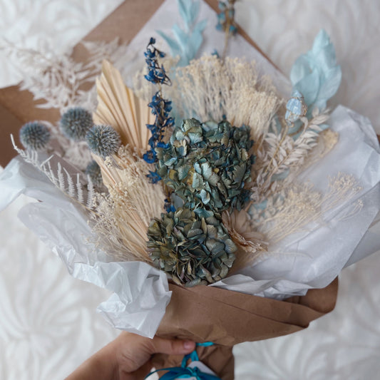A large flower bouquet featuring blue and white dried flowers
