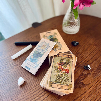 The Botanica Oculta Tarot Deck box, deck of cards, and guidebook displayed with crystals and candles