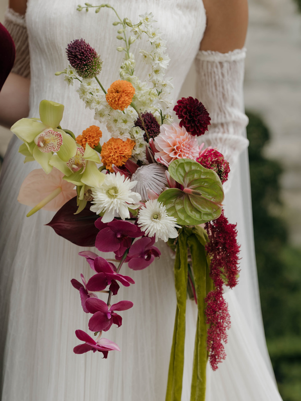 Up close shot of a bride holding her colorful bouquet full of unique ingredients like Orchids and Anthuriums.