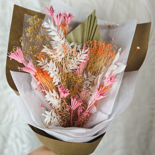 A bouquet of peach, white, pink, and tan dried flowers with a rhodochrosite crystal