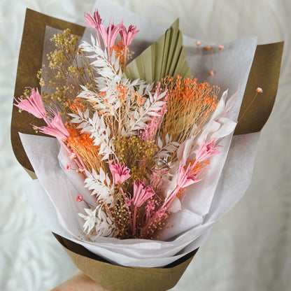 A bouquet of peach, white, pink, and tan dried flowers with a rhodochrosite crystal