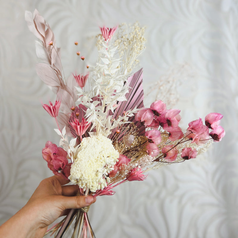 hand holding a bouquet of pink and white dried flowers