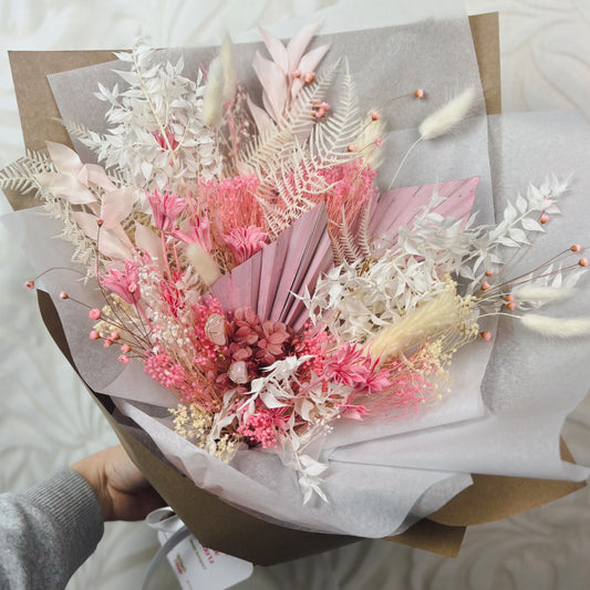 A bouquet of dried flowers, pink and white, with rose quartz crystals