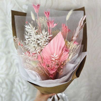 A white and pink dried flower bouquet with a rose quartz crystal