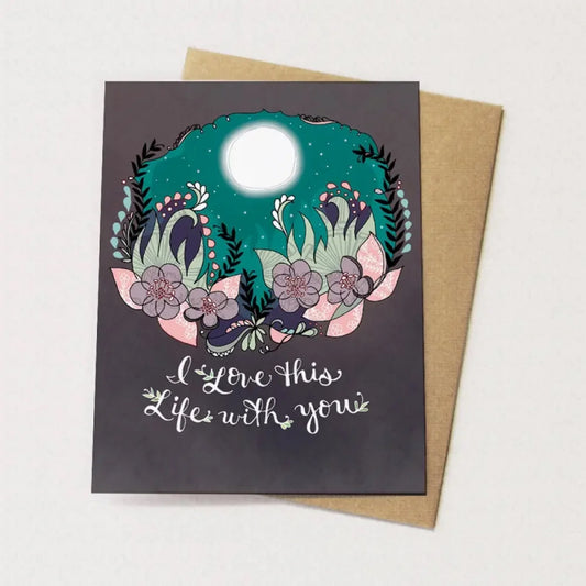 Greeting card with moon in the night sky with flowers that says "I love this life with you"