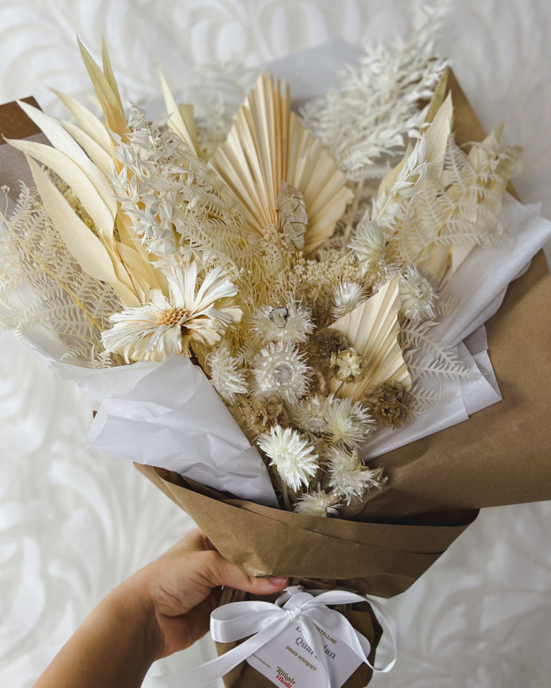 An all-white bouquet of dried flowers featuring a quartz crystal inside