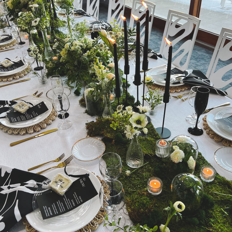 The top of a long table setting with lots of floral, greenery, and moss down the center