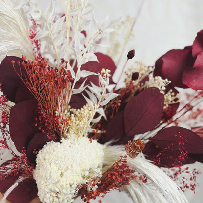 Dark red and white dried flower bouquet close up shot with a pigeon blood jasper crystal