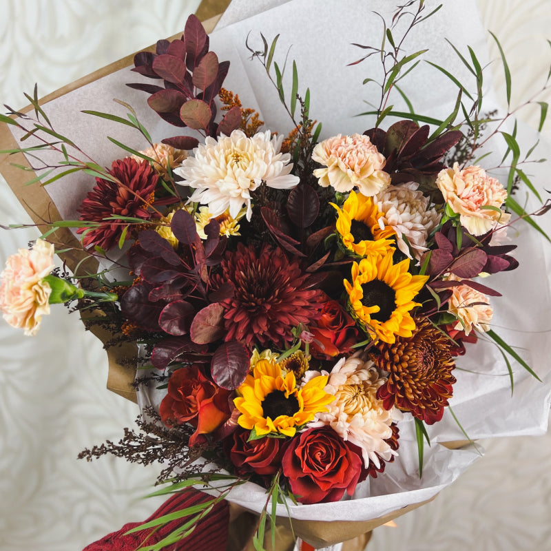 A large autumn flower bouquet featuring sunflowers, mums, and other fall favorites