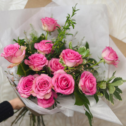 A dozen roses, pink, with greenery