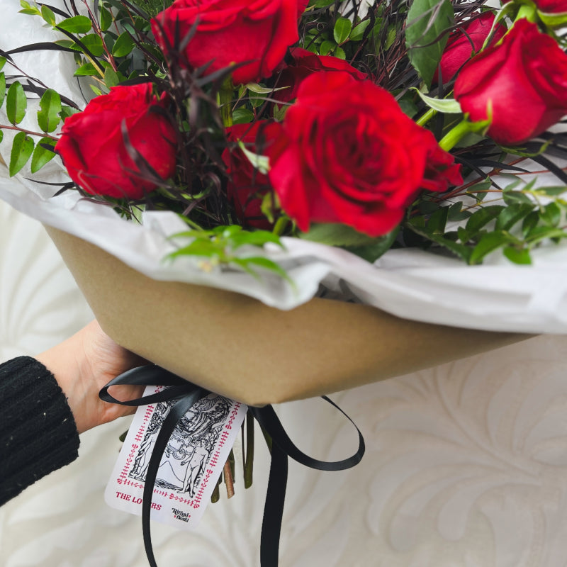 A The Lovers tarot card is tied to a bouquet of red roses