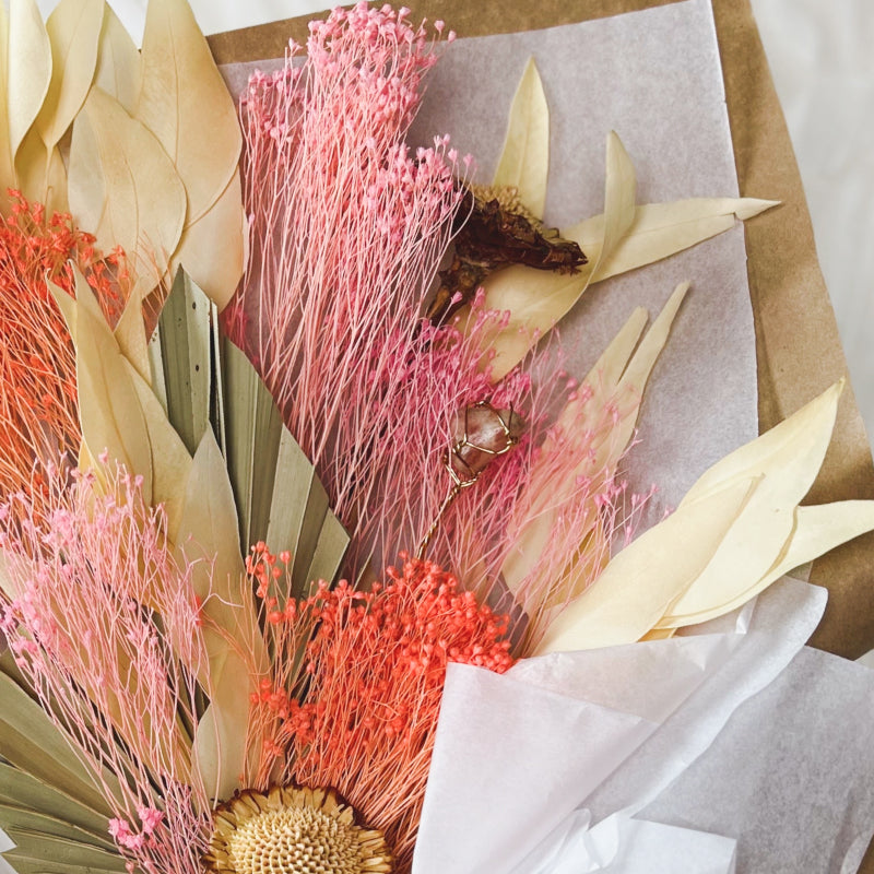A sun stone crystal displayed in a bouquet of dried flowers