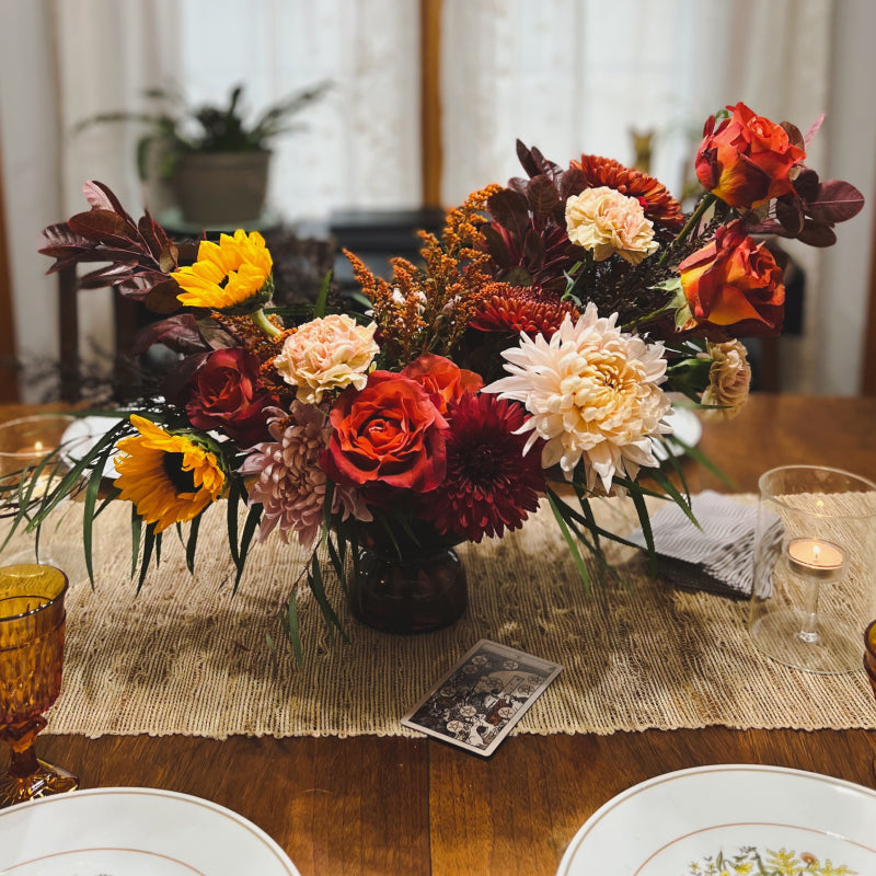 An abundant autumn centerpiece on a dinner table with a ten of coins tarot card