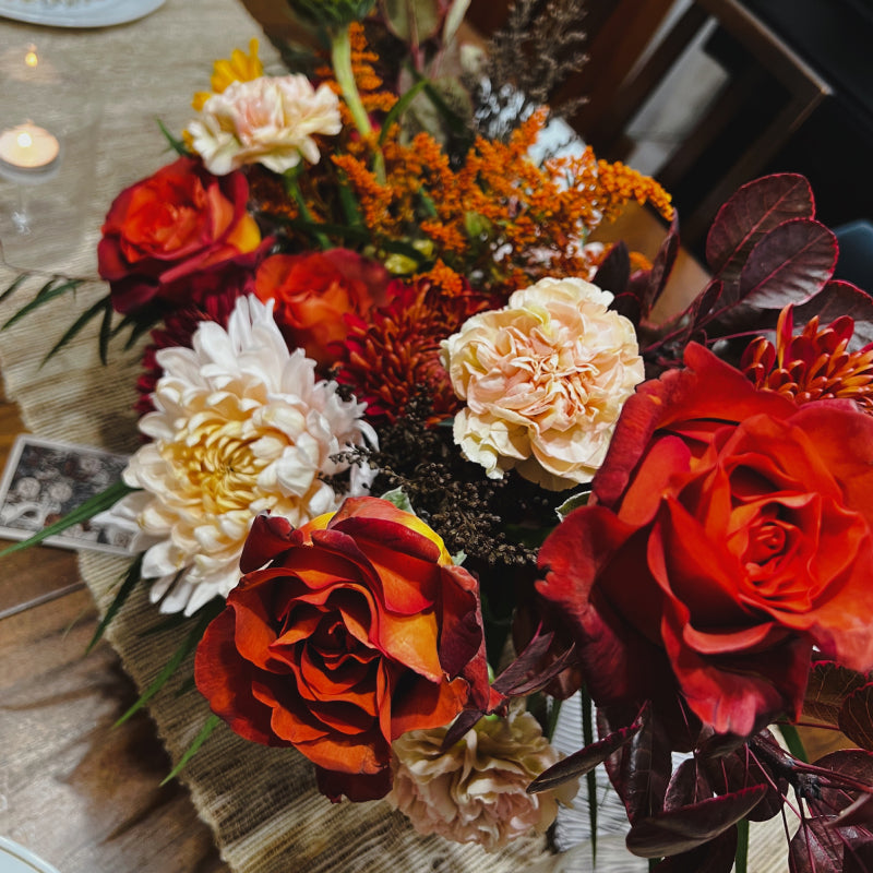 An up close view of an autumn centerpiece filled with fall flowers and foliage