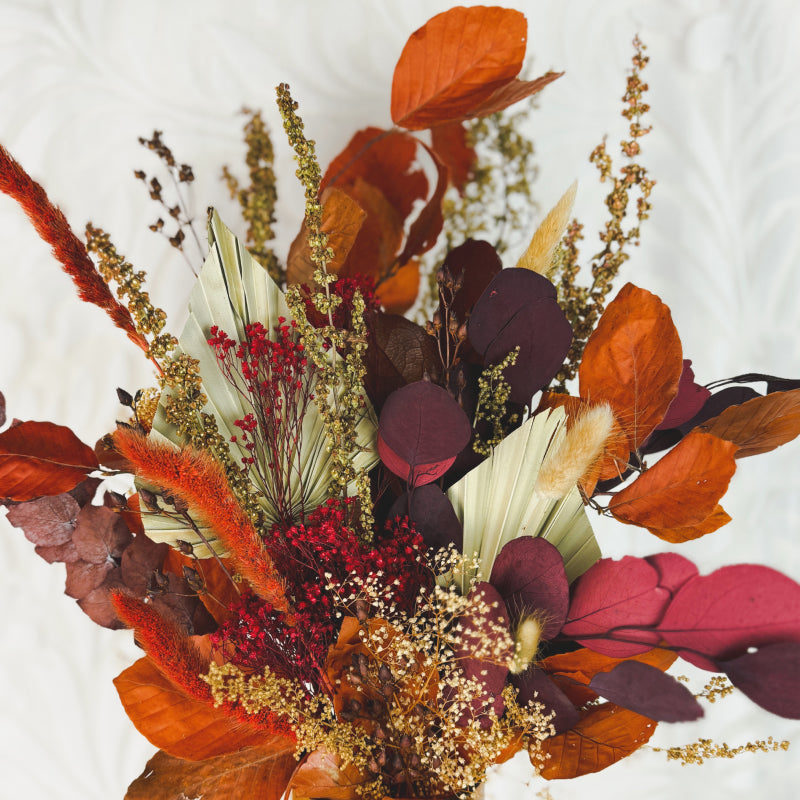 Close up of a brown, red, and orange fall dried flower bouquet