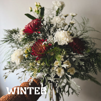 Seasonal winter flower bouquet featuring evergreens, berries, and red and white flowers