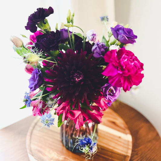 Small vase arrangement in an enchanting color palette of dark purples, magentas, and blues