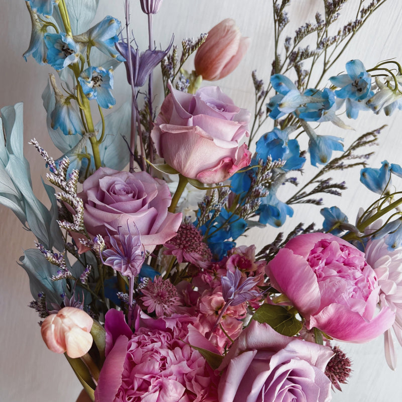 An up close view of a bouquet of flowers in a dreamy pastel color palette, featuring roses, peonies, and more