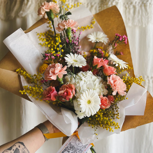 Wrapped bouquet of pink, yellow, and white flowers