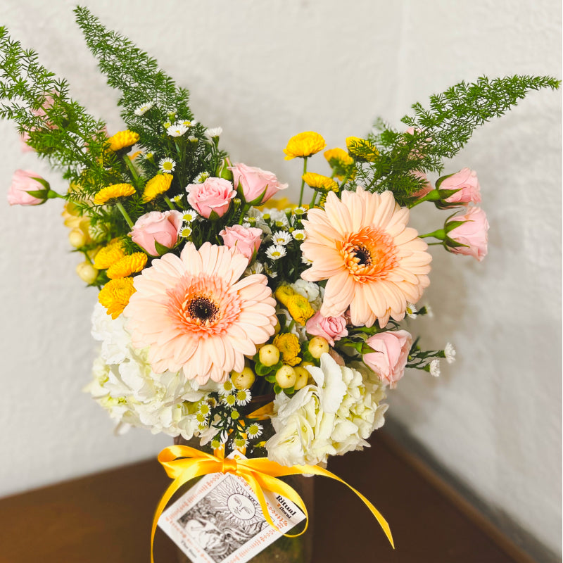 Peach-colored daisies and other pink, yellow and white flowers in a vase