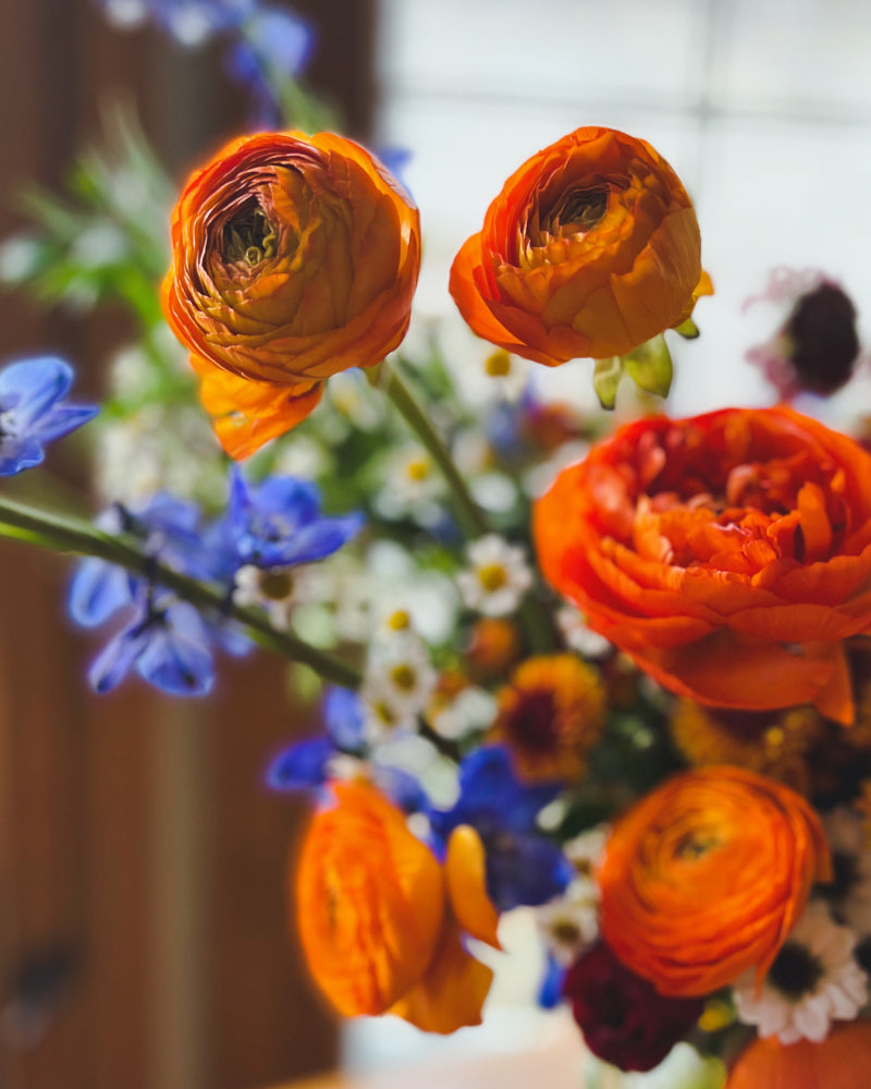 A detail shot of some orange ranunculus in a larger vase arrangement